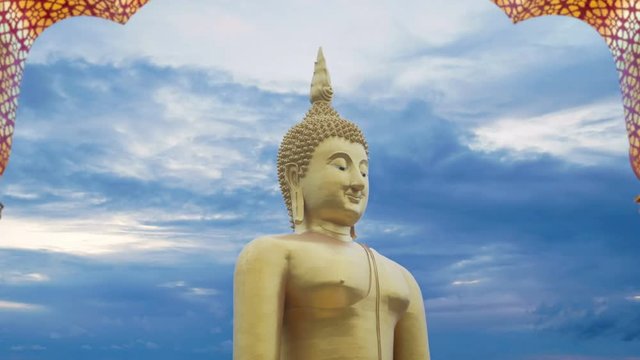 4K footage. big great powerful Buddha statue in gold color with door frame arch and beautiful time lapse of sky with cloudy at sunset or sunrise time at background. Buddha image for Buddhists