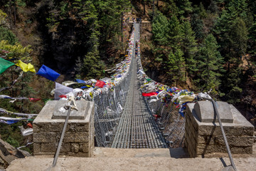 Landscape view of entrance to suspension bridge. One alpinist is passing over the bridge.Sagarmatha...