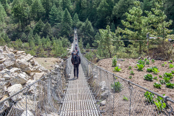 Landscape view of entrance to suspension bridge. One alpinist is passing over the bridge.Sagarmatha...