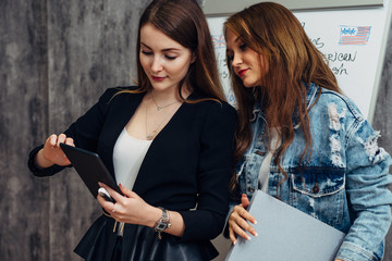 Two young women looking at screen of tablet PC using mobile application.