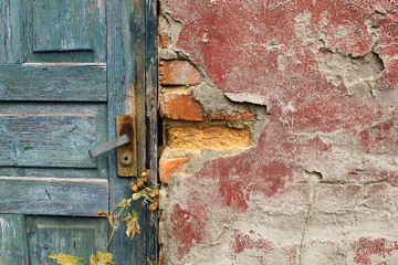 Old blue cracked wooden door with knob and padlock close up
