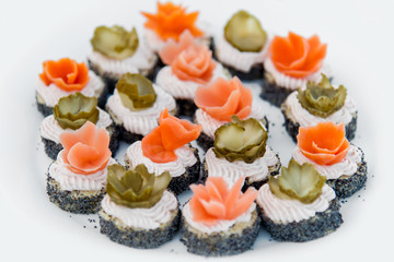 Close up of small canapes arranged on a plate over light background - selective focus