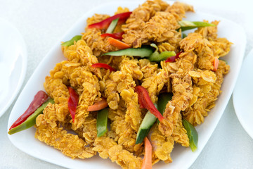 close-up of delicious crispy fried chicken breast strips on white plate, on a white table with pepper, cucumbers and carrots, easy recipe for outdoor picnic or party, view from above