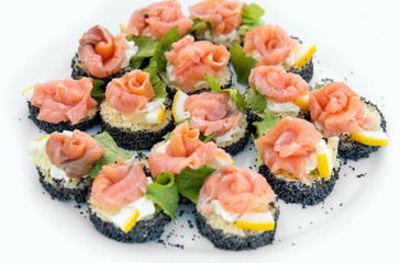 Close up of small canapes arranged on a plate over light background - selective focus