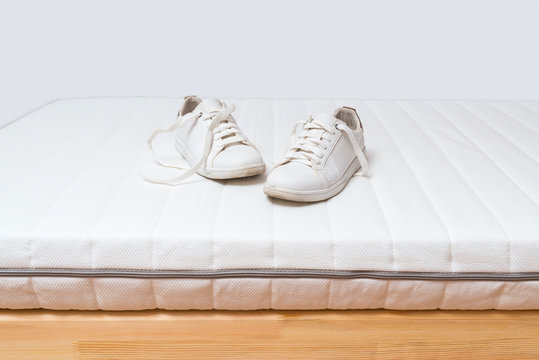 Dirty shoes on white clean mattress.