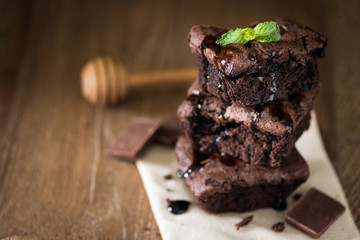 A stack of chocolate brownies on wooden background with mint leaf on top, homemade bakery and dessert