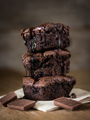 A stack of chocolate brownies on wooden background with mint leaf on top, homemade bakery and...