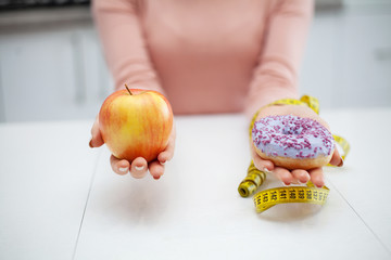 Dieting concept, beautiful young woman choosing between healthy food and junk food