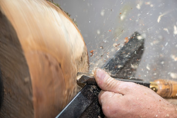 mortise chisel with sawdust on rotating piece of wood while forming a bowl