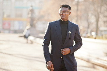 Amazingly looking african american man wear at blue blazer with brooch, black turtleneck and glasses posed at street. Fashionable black guy.