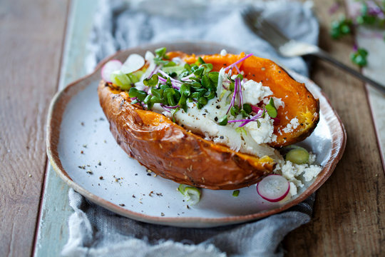 Sweet potato with mashed avocado, yogurt, feta cheese and sprouts