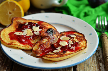 Pancakes with plums and almond flakes on a white plate