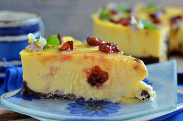 A piece of cheesecake with pieces of plum poured white chocolate on a glass plate