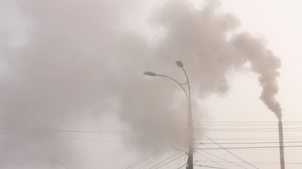 The pipe of the plant emits harmful substances into the atmosphere. Close-up on a sky background