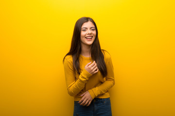 Obraz premium Teenager girl on vibrant yellow background smiling a lot while putting hands on chest
