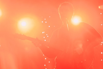 Rock band front man silhouette on a stage with guitar singing to microphone in colorful backlights 