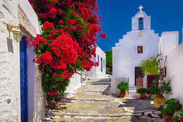 Traditional colorful mediterranean street with flowers and church, Cyclades, Greece
