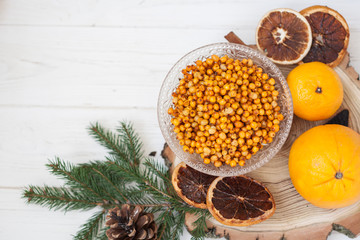 Obraz na płótnie Canvas Orange and sea buckthorn on a white wooden background, christmas food, concept of seasonal vitamins and healthy eating. Copy space