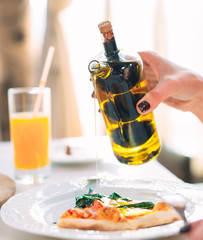 The girl pours oil Pizza.