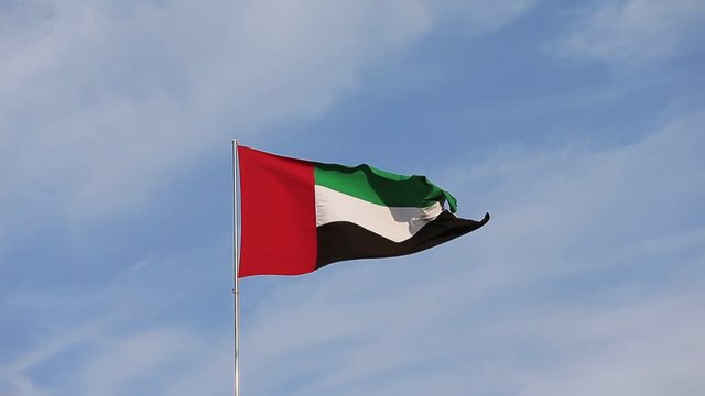 Flag waving in the sky, national symbol of United Arab Emirates. National Day concept.
