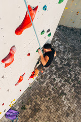 Muscular man practicing rock-climbing on a rock wall