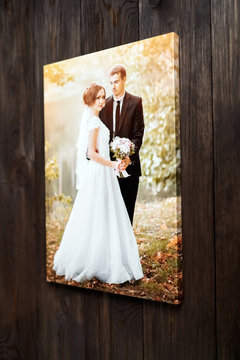 Photo of a wedding couple printed on canvas. Photography stretched on a frame hanging on a brown wooden wall. Sample gallery stretch
