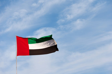 Flag waving in the sky, national symbol of United Arab Emirates. National Day concept.