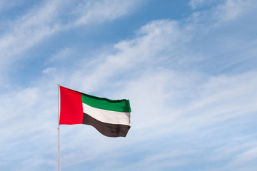 Flag waving in the sky, national symbol of United Arab Emirates. National Day concept.