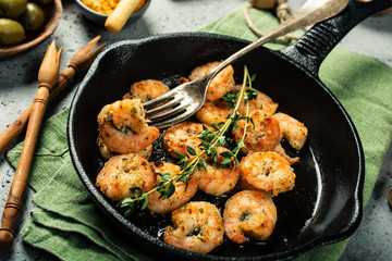 Prawns Shrimps roasted on frying cast iron pan with thyme and garlic. Party food background.