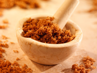 DARK BROWN CANE SUGAR IN PESTLE AND MORTAR