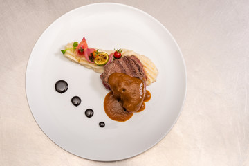 Pepper steak, served with potatoes, strawberry and cherry tomato