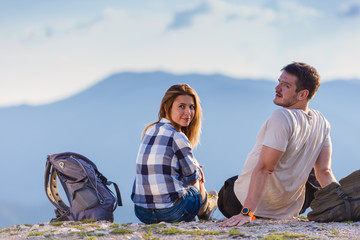 A couple enjoying the view on a peak of the mountain, cliff at sunset. Success, winners.