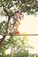 route in a rope park - a young girl on the obstacles