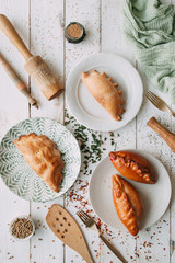 Pies and khachapuri on wooden light background. Food styling and cooking with fresh ingredients.