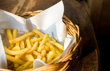 Tasty french fries in dish on wooden table background