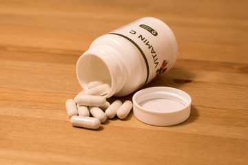 Medication of vitamin C bottle spilled on wooden table