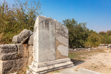 Detail of marble column with ancient Greek scripture and plinth at historic archaeological site of Miletus at Aydin privince, Turkey.