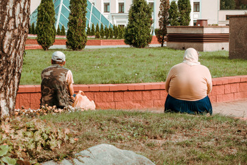 the fat woman is sitting on the bench. next lean man