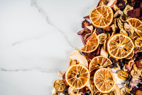 Home autumn harvest, dried fruits and berries in glass jars for canned preserves, strawberries, raspberries, apples, bananas, oranges, light concrete background, copy space