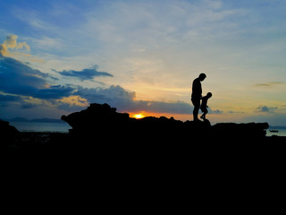 Silhouette of loving father and son walked on seaside and beautiful sunset background.