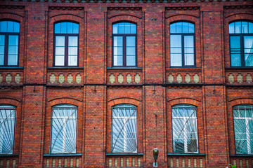 The facade of the building of red bricks with windows