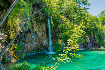 Nationalpark Plitvicer Seen in Kroatien.kleiner Wasserfall im Wald im Vordergrund ein See mit Büschen