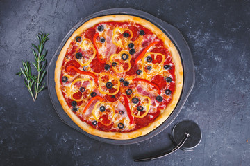 Pizza with cheese meat peppers and tomatoes on a dark background