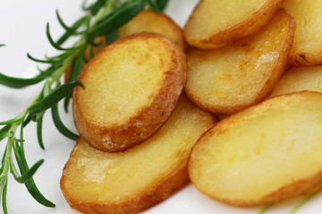 Crunchy fried potato slices with peel with fresh rosemary, closeup

