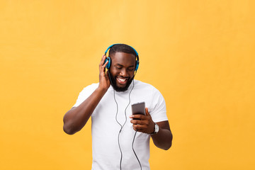 African American man with headphones listen and dance with music. Isolated on yellow background