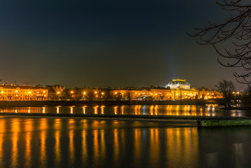 Illuminated classical buildings and street lights reflecting on the Vltava river in Prague before a small waterfall in a cold winter night - 4
