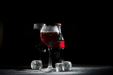 The breaking of a glass with fragments. The explosion of a glass on a black background with a colored liquid. Splashes of colors.