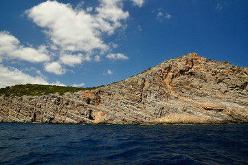Fototapeta na wymiar A Beautiful Sun Lit Cliff Surrounded by Dark Blue Sea