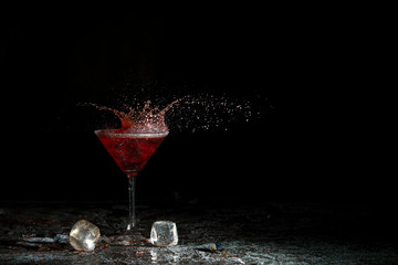 The breaking of a glass with fragments. The explosion of a glass on a black background with a colored liquid. Splashes of colors.