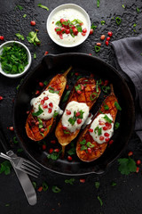 Grilled eggplants with yogurt sauce, pomegranate seeds, parsley and green onion in cast iron vintage pan.
